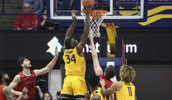West Virginia forward Oscar Tshiebwe (34) makes a basket as he is defended by Austin Peay center Matheus Silveira (24) during the first half of an NCAA college basketball game Thursday, Dec. 12, 2019, in Morgantown, W.Va. (AP Photo/Kathleen Batten)