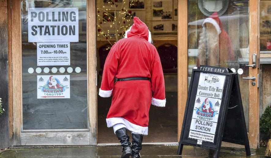 A man dressed as Father Christmas enters his grotto at the Dunster Tithe Barn near Minehead, Somerset, England which is being used as a polling station in the 2019 general election, Thursday Dec. 12, 2019. Britain is holding an early election in wintry December, with a number of strange locations put in use as polling places. Among the places where Britons cast their ballots Tuesday were a car dealership, a laundrette, a Christmas grotto and of course some pubs. There were a few problems, including flooding at one location. (Ben Birchall/PA via AP)