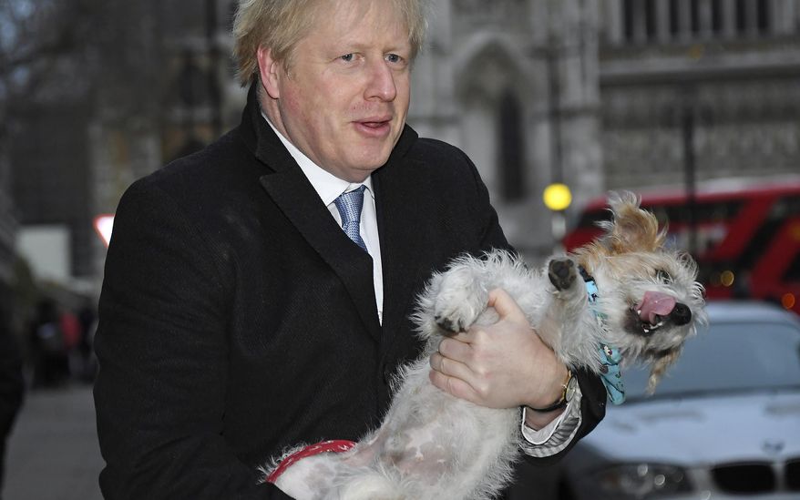 Britain's Prime Minister and Conservative Party leader Boris Johnson holds his dog Dilyn after voting in the general election at Methodist Central Hall, Westminster, London, Thursday Dec. 12, 2019. Dogs wait outside while their owners go into polling stations to cast their ballot in a general election Thursday Dec. 12, 2019. U.K. voters are deciding Thursday who they want to resolve the stalemate over Brexit in a parliamentary election widely seen as one of the most decisive in modern times. (AP Photo/Alberto Pezzali)