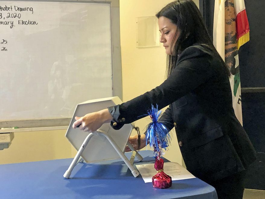 Wesley Keller, who works for the California Secretary of State's Elections Division, draws canisters containing alphabet letters that will determine the order that candidates' names will appear on the March 3, 2020, California primary ballot, Thursday, Dec. 12, 2019 in Sacramento. (AP Photo/Kathleen Ronayne)