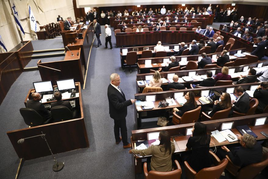 Blue and White party leader Benny Gantz, center, stands during a Knesset session in Jerusalem, Wednesday, Dec. 11, 2019. The Israeli parliament began voting to dissolve itself on Wednesday and pave the path to an unprecedented third election within a year. (AP Photo/Oded Balilty)