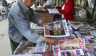 A man looks through newspapers with front pages leading with Myanmar leader Aung San Suu Kyi at the International Court of Justice hearing, near a roadside journal shop Thursday, Dec. 12, 2019, in Yangon, Myanmar. Suu Kyi testified to the court that the exodus of hundreds of thousands of Rohingya Muslims to neighboring Bangladesh was the unfortunate result of a battle with insurgents. She denied that the army had killed civilians, raped women and torched houses. (AP Photo/Thein Zaw)