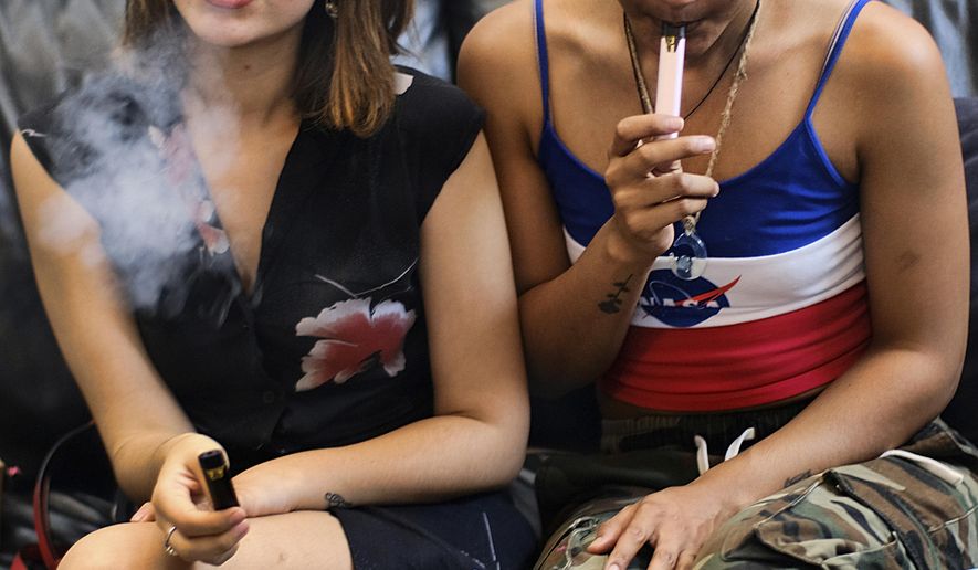 FILE - In this Saturday, June 8, 2019, file photo, two women smoke cannabis vape pens at a party in Los Angeles. On Thursday, Dec. 12, 2019, U.S. health officials said 26 states have reported deaths, for a total of 52. (AP Photo/Richard Vogel, File)