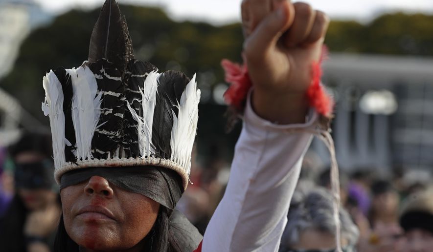 A woman performs the feminist anthem "A rapist in your path," in a demonstration against gender-based violence, in front of the Supreme Court, in Brasilia, Brazil, Friday, Dec. 13, 2019. (AP Photo/Eraldo Peres)