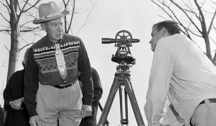 In this April 18, 1958 file photo, Philip N. Brooks, right, a New York State surveyor, takes a look through his transit on the Tuscarora Indian Reservation near Niagara Falls, N.Y., while Tuscarora Chief Elton Black Cloud Greene watches. The tribe is resisting state seizure of their land for a power project. In 1959, the U.S. government started the switch from the U.S. survey foot to the international foot, and it will finish the job in 2022. (AP Photo)