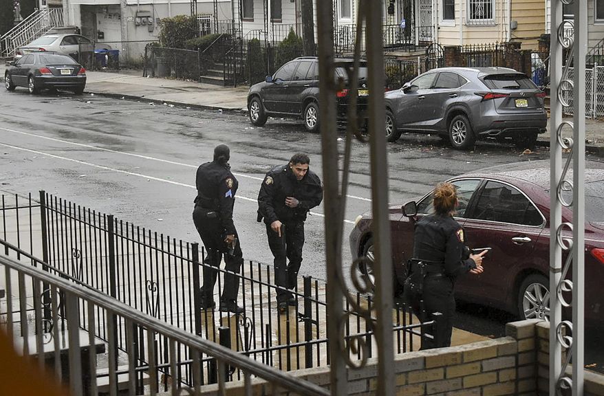 In this Dec. 10, 2019, photo, Jersey City police Sgt. Marjorie Jordan, left, helps fellow officer Raymond Sanchez to safety after he was shot during a gunfight that left multiple dead in Jersey City, N.J. The two killers were armed with a variety of weapons, including an AR-15-style rifle and a shotgun that they were wielding when they stormed into a store in an attack that left the scene littered with several hundred shell casings, broken glass and a community in mourning. Despite years of New Jersey officials focusing on the problems of crime guns coming into the state, Tuesday's shooting shows efforts are falling short. (Justin Moreau via AP)
