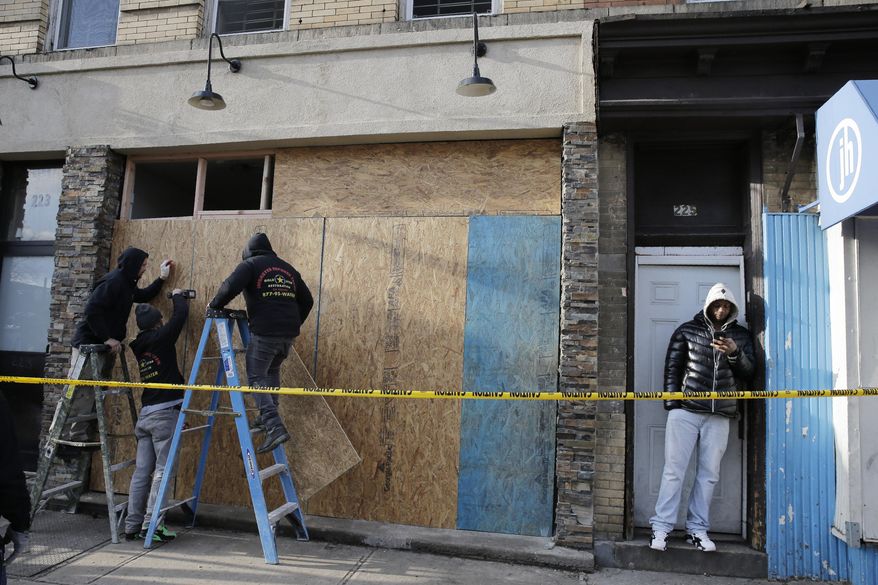 People board up the front of a kosher supermarket thats was the site of a gun battle in Jersey City, N.J., Wednesday, Dec. 11, 2019. The two gunmen in a furious firefight that left multiple people dead in Jersey City clearly targeted the Jewish market, the mayor said Wednesday, amid growing suspicions the bloodshed was an anti-Semitic attack. (AP Photo/Seth Wenig)