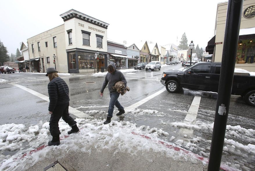 FILE - In this Wednesday, Nov. 27, 2019, file photo, a pair of pedestrians try to avoid a slushy gutter in downtown Nevada City, Calif. Recent heavy storms in California have wiped out much of the state's abnormally dry conditions. Two months ago, the U.S. Drought Monitor categorized more 81% of the state as abnormally dry because of above-normal temperatures and a lack of precipitation six weeks into the water year that started Oct. 1, 2019. The percentage climbed to 85% as recently as last week. (Elias Funez/The Union via AP,File)