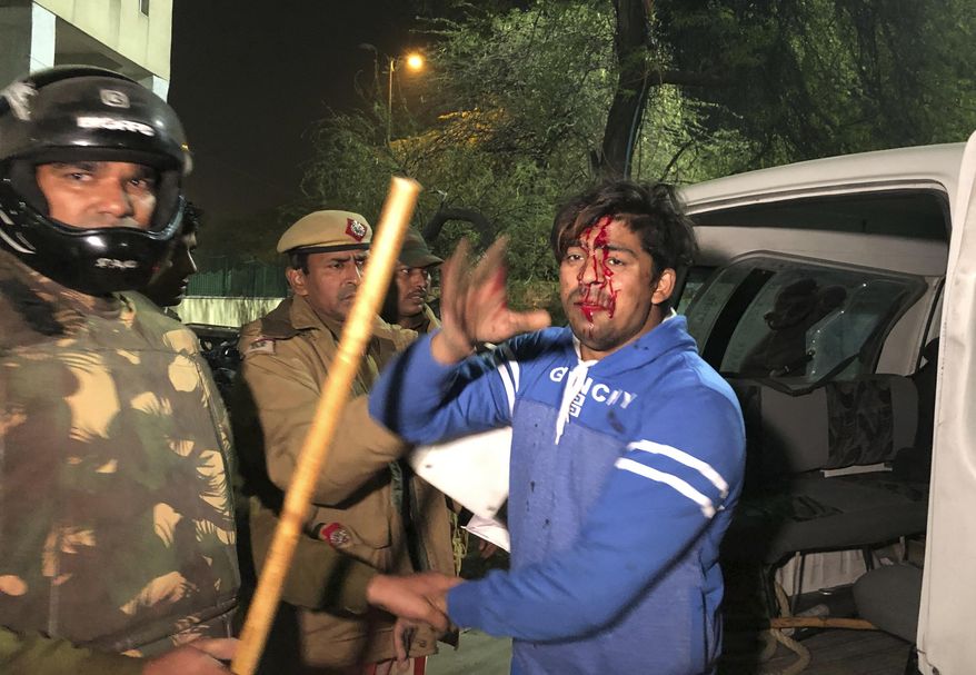 Policemen detain an injured student outside Jamia Millia Islamia university during a protest against Citizenship Amendment Act in New Delhi, India, Sunday, Dec. 15, 2019. Protests have been continuing over a new law that grants Indian citizenship based on religion and excludes Muslims. (AP Photo/Saaliq Sheikh)