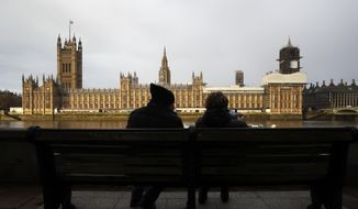 A couple takes photos of Houses of Parliament in London, Saturday, Dec. 14, 2019.  With his hefty government majority, Prime Minister Boris Johnson is set to start the process next week of pushing Brexit legislation through Parliament to ensure Britain leaves the EU by the Jan. 31 deadline. (AP Photo/Thanassis Stavrakis)