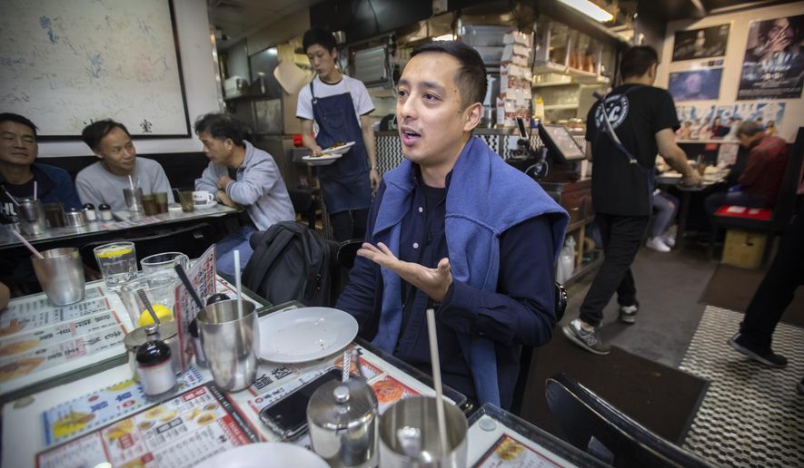 In this Dec. 13, 2019, photo, Martin Khan of Capital Cafe talks about the effects on his business after he says his store was incorrectly labeled as an anti-protest "blue" shop on online apps in Hong Kong. Protesters in Hong Kong are increasingly using their spending power to punish businesses they deem hostile to their cause. Apps are assigning color-coded labels to stores to help guide consumers. Protest-friendly stores are categorized as yellow. Blue is used to identify shops suspected of opposing protests. Protesters believe that by boycotting supposedly pro-establishment businesses, they can help shift the balance of power and wealth in the semi-autonomous Chinese territory. (AP Photo/Mark Schiefelbein)