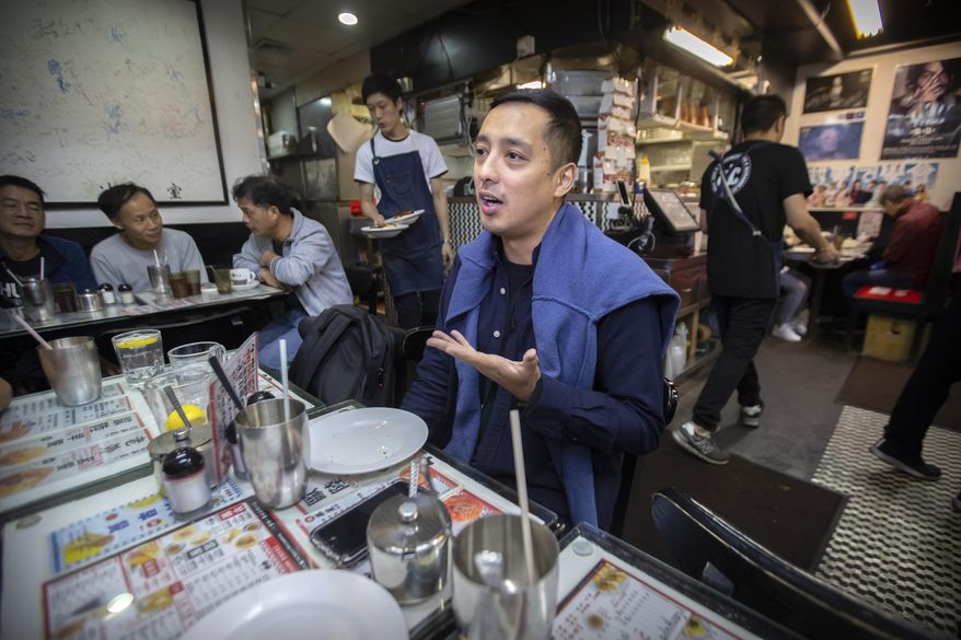 In this Dec. 13, 2019, photo, Martin Khan of Capital Cafe talks about the effects on his business after he says his store was incorrectly labeled as an anti-protest "blue" shop on online apps in Hong Kong. Protesters in Hong Kong are increasingly using their spending power to punish businesses they deem hostile to their cause. Apps are assigning color-coded labels to stores to help guide consumers. Protest-friendly stores are categorized as yellow. Blue is used to identify shops suspected of opposing protests. Protesters believe that by boycotting supposedly pro-establishment businesses, they can help shift the balance of power and wealth in the semi-autonomous Chinese territory. (AP Photo/Mark Schiefelbein)