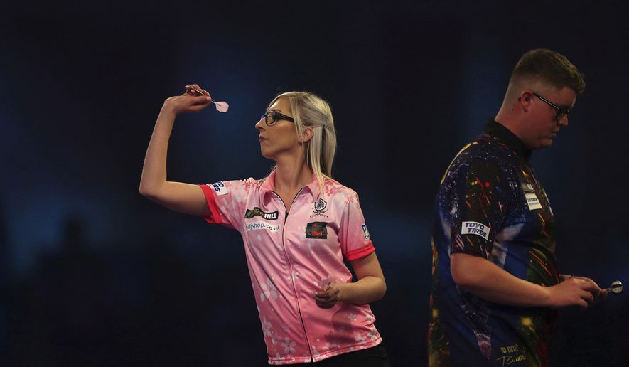 Fallon Sherrock and Ted Evetts in action at the PDC Darts World Championship at Alexandra Palace, London, Tuesday Dec. 17, 2019. Sherrock become the first female player to beat a man at the PDC World Championship after she recovered from losing the opening set to beat Ted Evetts 3-2 in front of a raucous crowd at Alexandra Palace. (Steven Paston/PA via AP)