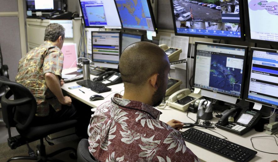FILE - In this Dec. 1, 2017, file photo, Hawaii Emergency Management Agency officials work at the department's command center in Honolulu. A defense bill expected to be passed by the U.S. Senate on Tuesday, Dec. 17, 2019, includes a provision taking away the authority and responsibility for notifying residents of incoming missiles from local emergency managers. Instead it gives that job to the U.S. government. U.S. Sen. Brian Schatz authored the measure after officials in his home state of Hawaii mistakenly sent cellphone and broadcast alerts to the public warning of a ballistic missile attack in 2018. (AP Photo/Caleb Jones, File)