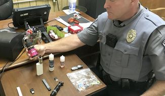 FILE - In this Sept. 23, 2019 photo, Bristol, Va., Police Officer Marlin Goff shows some of the vaping products he has confiscated from students at a high school. Congress is moving to pass the biggest new sales restrictions on tobacco products in more than a decade, with support in 2019 from two unlikely backers: Marlboro-cigarette maker Altria and vaping giant Juul Labs. (Tim Dotson/Bristol Herald Courier via AP)