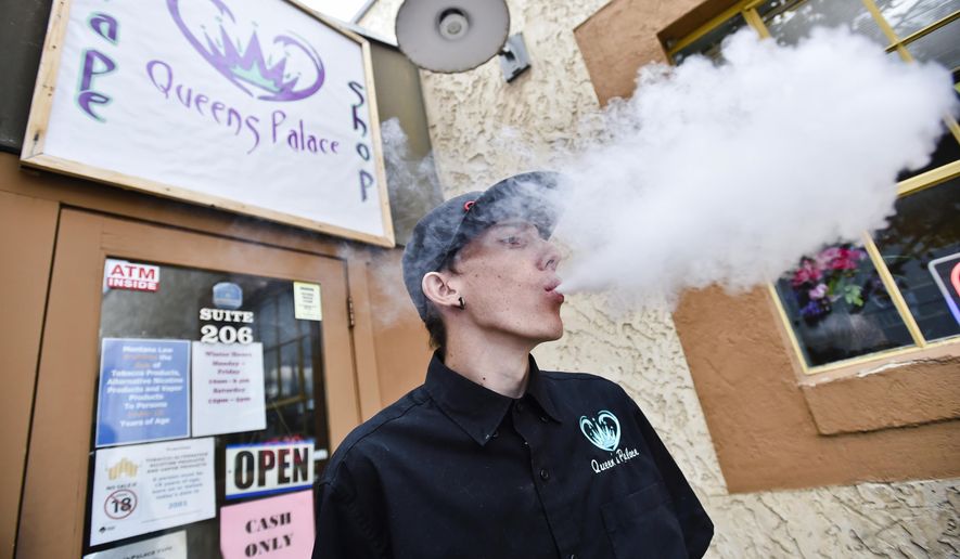 In this Oct. 17, 2019 photo, Caleb Banner, a former Queen&#x27;s Palace vape shop employee, exhales a cloud of vape outside the store in Helena, Mont. Montana officials temporarily banned flavored e-cigarettes Wednesday, Dec. 18, 2019, after a judge ruled against vape shop owners who sued the state to keep their products on the shelves. (Thom Bridge/Independent Record via AP)