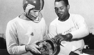 FILe - In this, San Francisco 49ers fullback Joe Perry, right, shows quarterback Y. A. Tittle the plastic mask he has worn during the football season to protect his bridgework, during practice at Menlo Park, Calif. Tittle, who suffered a cheekbone fracture against the Detroit Lions, is wearing the mask he has used since. Helmets have evolved from the original hard leather of the NFL’s infancy to hard polycarbonate single-piece shells with various amounts of padding and air bladders that served as the primary form of head protection into the beginning of this century.  (AP Photo/File)