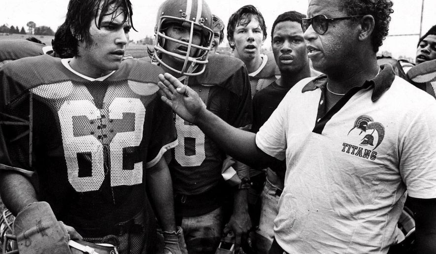 File= This 1971 file photo shows Alexandria, Va's., T.C. Williams High School football coach Herman Boone, right, during a break at summer camp, with guard Johnny Colantuoni, (62) and John Vaughn, center. Boone, the Virginia high school football coach who inspired the movie “Remember the Titans,” has died. He was 84. Boone guided T.C. Williams High School to a state championship while navigating the early days of desegregation. Aly Khan Johnson, an assistant coach for Boone beginning in 1972, said the coach died Wednesday, Dec. 18, 2019, at his home In Alexandria, Va. Johnson said a funeral home operated by his wife is handling the arrangements, which are not complete. (AP Photo/File)