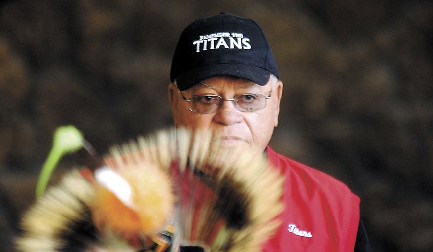 This Feb. 22, 2005, file photo shows Herman Boone, the coach featured in the movie "Remember the Titans" peering over the headdress of a Shoshone-Bannock dancer to speak to a large crowd in Pocatello, Idaho. Boone, the Virginia high school football coach who inspired the movie “Remember the Titans,” has died. He was 84. Boone guided T.C. Williams High School to a state championship while navigating the early days of desegregation. Aly Khan Johnson, an assistant coach for Boone beginning in 1972, said the coach died Wednesday, Dec. 18, 2019, at his home In Alexandria, Virginia. Johnson said a funeral home operated by his wife is handling the arrangements, which are not complete.(Joshua Duplechian/The Idaho State Journal via AP, File)
