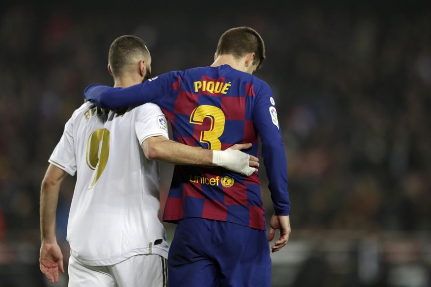 Real Madrid's Karim Benzema, left, and Barcelona's Gerard Pique walks together on the pitch during a Spanish La Liga soccer match between Barcelona and Real Madrid at Camp Nou stadium in Barcelona, Spain, Wednesday, Dec. 18, 2019. Thousands of Catalan separatists are planning to protest around and inside Barcelona's Camp Nou Stadium during Wednesday's "Clasico". (AP Photo/Bernat Armangue)