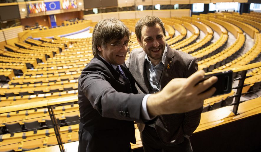 Catalonia&#39;s former regional president Carles Puigdemont, left, and former Catalan regional minister Antoni Comin take a selfie overlooking the plenary chamber at the European Parliament in Brussels, Friday, Dec. 20, 2019. In a potentially stinging reversal for Spanish justice authorities, the European Union&#39;s top court ruled that a former Catalan official serving a prison sentence for his role in a banned independence referendum two years ago had the right to parliamentary immunity when he was on trial. (AP Photo/Francisco Seco)