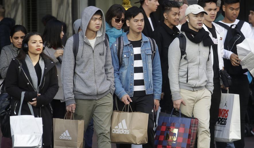 FILE - In this Nov. 29, 2019, file photo shoppers carry bags as they cross a street in San Francisco. Black Friday kicks off the start of the holiday shopping season. On Friday, Dec. 20, the Commerce Department issues its November report on consumer spending, which accounts for roughly 70 percent of U.S. economic activity. (AP Photo/Jeff Chiu, File)