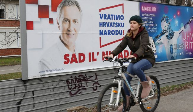In this Thursday, Dec. 19, 2019 photo, a cyclist rides past a poster of presidential candidate Miroslav Skoro in Zagreb, Croatia. The European Union&#x27;s newest member state Croatia is holding a tight presidential election this weekend, only days before it takes over the EU presidency for the first time. (AP Photo/Darko Bandic)