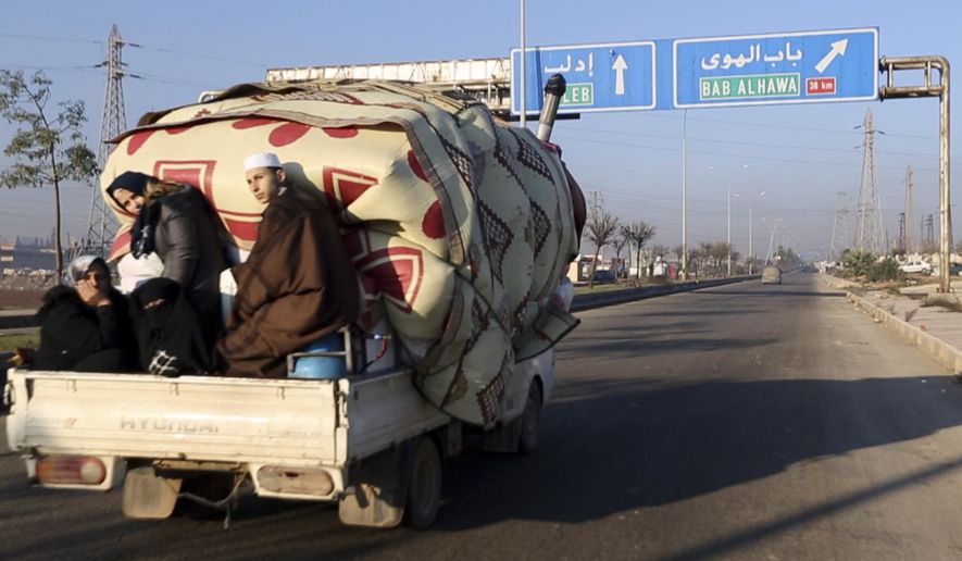 In this frame grab from video taken on Thursday, Dec. 19, 2019, a family with their goods loaded on a lorry drives towards the Turkish border in Syria's rebel-controlled Idlib province. The UN says that some 60,000 Idlib residents have been displaced in recent weeks by a government offensive aimed at dislodging the rebels from their last stronghold in the country.(AP Photo/APTN)