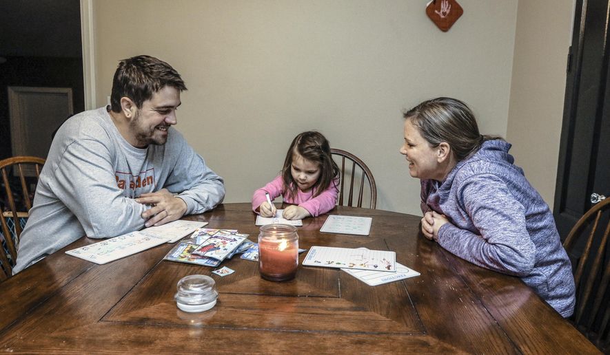 In this Friday, Dec. 13, 2019, photo, Stephen Wilhite, left, and fiancee Amanda Wedding, sit at the kitchen table and go over homework with Wedding's daughter, Callie, 4, at their home in Owensboro, Ky. The St. Benedict's Homeless Shelter in Owensboro helped Wilhite rebuild a life destroyed by drugs. (Greg Eans/The Messenger-Inquirer via AP)