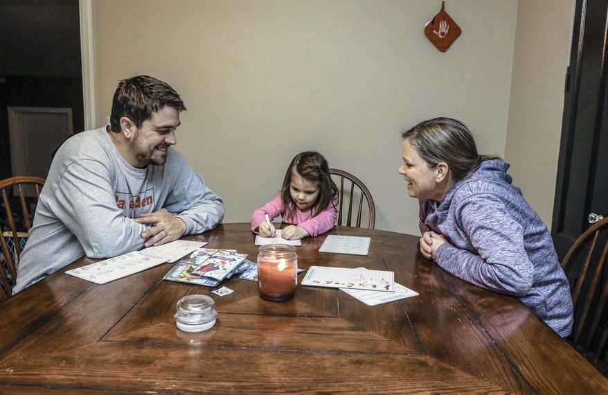 In this Friday, Dec. 13, 2019, photo, Stephen Wilhite, left, and fiancee Amanda Wedding, sit at the kitchen table and go over homework with Wedding's daughter, Callie, 4, at their home in Owensboro, Ky. The St. Benedict's Homeless Shelter in Owensboro helped Wilhite rebuild a life destroyed by drugs. (Greg Eans/The Messenger-Inquirer via AP)