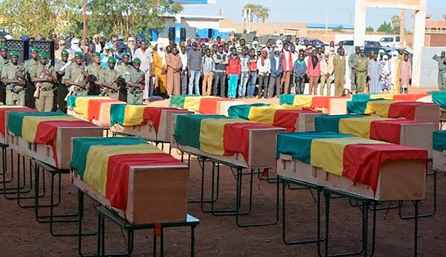 This photo made available from the Mali Army, shows coffins being honored at a funeral ceremony in Gao, Mali, Wednesday, Nov. 20, 2019. The Mali Defense Ministry held a funeral for the 30 soldiers killed in a Monday attack on an army patrol by extremists near the border with Niger. (Mali Army via AP) ** FILE **
