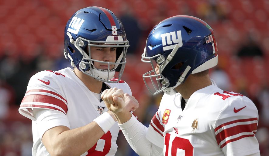 New York Giants quarterback Daniel Jones (8) and quarterback Eli Manning (10) talk while working out prior to an NFL football game against the Washington Redskins, Sunday, Dec. 22, 2019, in Landover, Md. (AP Photo/Alex Brandon) **FILE**