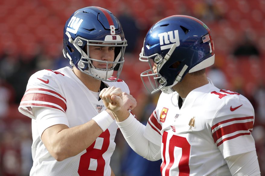 New York Giants quarterback Daniel Jones (8) and quarterback Eli Manning (10) talk while working out prior to an NFL football game against the Washington Redskins, Sunday, Dec. 22, 2019, in Landover, Md. (AP Photo/Alex Brandon) **FILE**