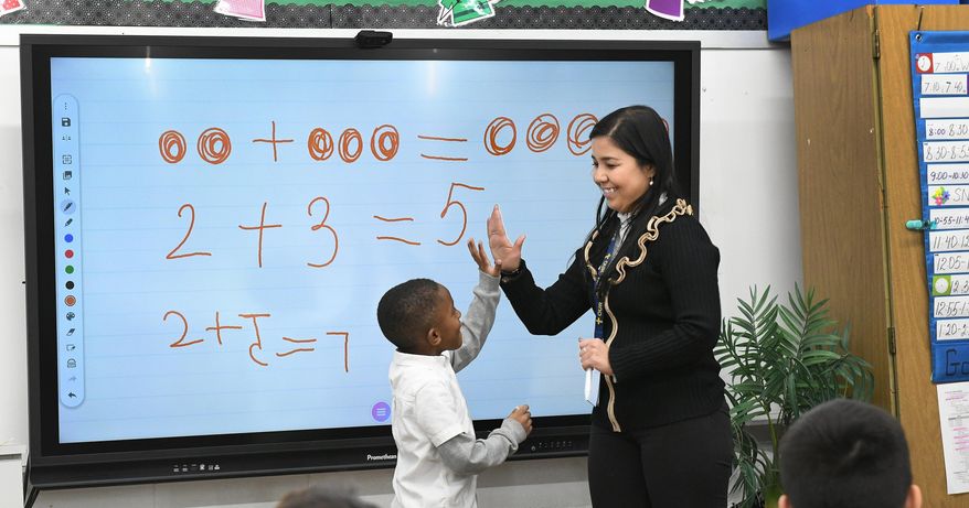 Teaching assistant Dilia Samadova teaches a math lesson in Mrs. Zenobi's kindergarten class at Our Lady of Peace School, in Canton, Ohio on Wednesday, Dec. 11, 2019. (Ray Stewart/The Canton Repository via AP)