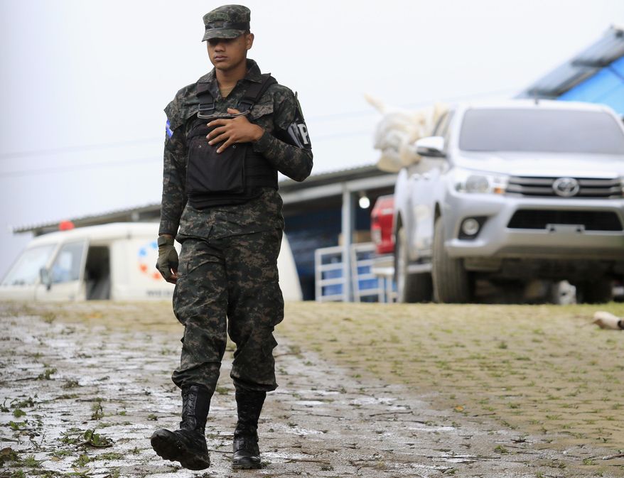 A military police officer walks past a pick-up truck loaded with the bodies of dead inmates that is parked in the Tela prison where at least 18 prisoners were killed during an prisoner’s riot on Friday in Tela, Honduras, Saturday, Dec. 21, 2019. The riot came several days after Honduras declared a state of emergency in its prison system. (AP Photo/Delmer Martinez)