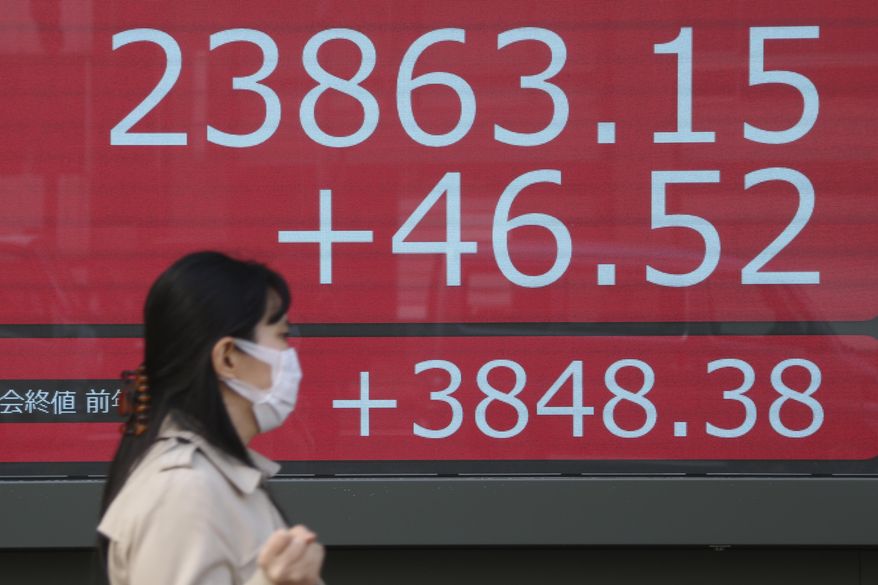 A woman walks by an electronic stock board of a securities firm in Tokyo, Monday, Dec. 23, 2019. Shares were mixed Monday in quiet trading ahead of Christmas holidays for many markets. (AP Photo/Koji Sasahara)
