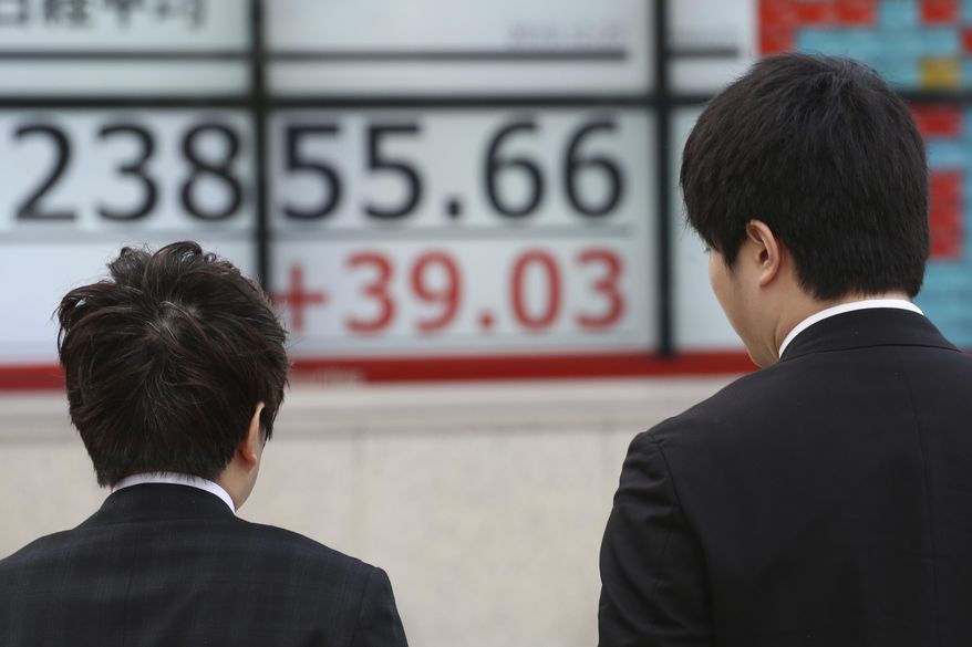 People walk by an electronic stock board of a securities firm in Tokyo, Monday, Dec. 23, 2019. Shares were mixed Monday in quiet trading ahead of Christmas holidays for many markets. (AP Photo/Koji Sasahara)
