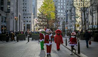 In this Friday, Dec. 20, 2019 photo, costumed performers leave Rockefeller Center  in New York. Some performers, who solicit tips from tourists from designated &amp;quot;activity zones&amp;quot; in Times Square, have been migrating to Rockefeller Center for the holiday season where no such zones exist. (AP Photo/Bebeto Matthews)