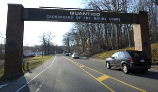 Cars pass under a sign at the entrance to the main gate at Quantico Marine Corps Base in Quantico, Va., Friday, March 22, 2013. A Marine killed a male and female colleague in a shooting at a base in northern Virginia before killing himself, officials said early Friday.  (AP Photo/Cliff Owen)