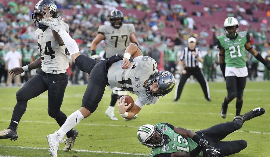 Central Florida quarterback Dillon Gabriel (11) leaps into the end zone for a touchdown over Marshall safety Nazeeh Johnson (13) during the Gasparilla Bowl NCAA college football game Monday, Dec. 23, 2019, in Tampa, Fla. (Stephen M. Dowell/Orlando Sentinel via AP)