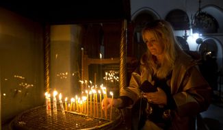 A visitor lights a candle at the Church of the Nativity built on top of the site where Christians believe Jesus Christ was born on Christmas Eve, in the West Bank City of Bethlehem, Tuesday, Dec. 24, 2019. (AP Photo/Majdi Mohammed)