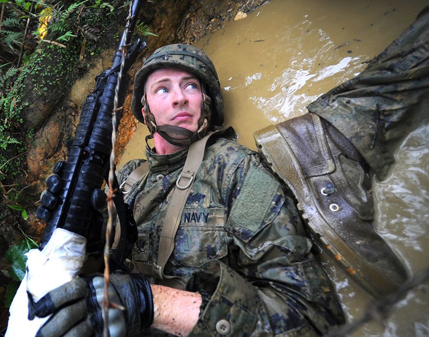 Construction Mechanic 3rd Class Denim Pettit , assigned to Naval Mobile Construction Battalion (NMCB) 3, lets a fellow squad member push off his arm while running a six-hour endurance course at the Marine Corps Jungle Warfare Training Center. More than 60 Seabees from NMCB-3 participated in an eight-day training program at the center. (U.S. Navy photo by Mass Communication Specialist 1st Class Chris Fahey/Released)