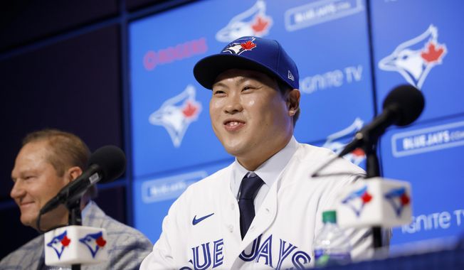 Toronto Blue Jays newly signed pitcher Hyun-Jin Ryu, right, smiles as he speaks to media at a news conference announcing his signing to the team in Toronto, Friday, Dec. 27, 2019. (Cole Burston/The Canadian Press via AP)