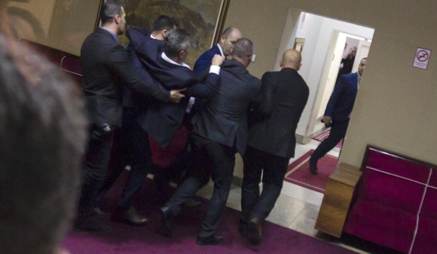 Police officers carry a pro-Serb opposition lawmaker in the parliament building in Podgorica, Montenegro, Friday, Dec. 27, 2019. The Serbian Orthodox Church says the law will strip it of its property, including medieval monasteries and churches. The government has denied that. Montenegro's parliament adopted a contested law on religious rights after chaotic scenes in the assembly that resulted in the detention of all pro-Serb opposition lawmakers. (AP Photo)