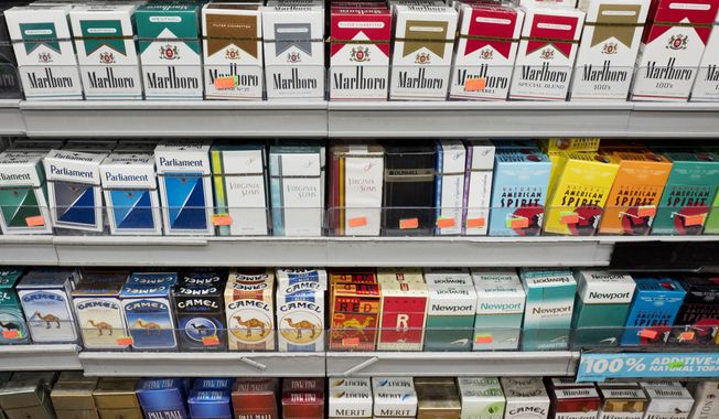 FILE - This Aug. 28, 2017 file photo shows cigarettes displayed on a store shelf in New York. With a new law enacted in December 2019, anyone under 21 can no longer legally buy cigarettes, cigars or any other tobacco products in the U.S. It also applies to electronic cigarettes and vaping products that heat a liquid containing nicotine. (AP Photo/Mark Lennihan, File)