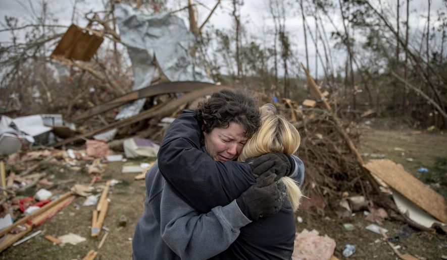 FILE - In this March 4, 2019 file photo, Carol Dean, left, cries while embraced by Lawanda Anderson as Dean sifts through the debris of the home she shared with her husband, David Wayne Dean, who died when a tornado destroyed the house in Beauregard, Ala. This was one of the top stories in Alabama in 2019 .(AP Photo/David Goldman, File)