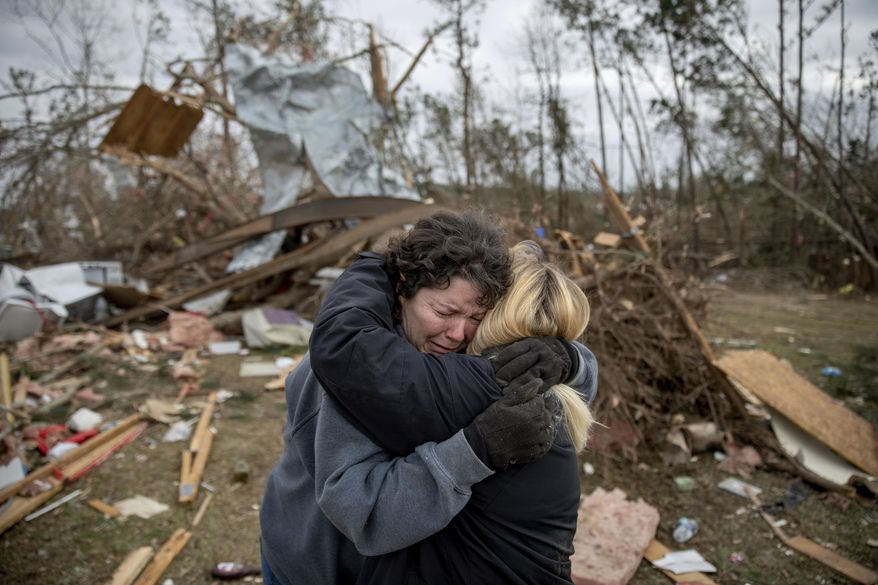 FILE - In this March 4, 2019 file photo, Carol Dean, left, cries while embraced by Lawanda Anderson as Dean sifts through the debris of the home she shared with her husband, David Wayne Dean, who died when a tornado destroyed the house in Beauregard, Ala. This was one of the top stories in Alabama in 2019 .(AP Photo/David Goldman, File)