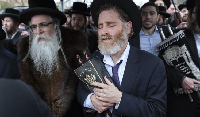 Community members, including Rabbi Chaim Rottenberg, left, celebrate the arrival of a new Torah near the rabbi&#x27;s residence in Monsey, N.Y. A day earlier, a knife-wielding man stormed into the home and stabbed multiple people as they celebrated Hanukkah in the Orthodox Jewish community. (AP Photo/Craig Ruttle)