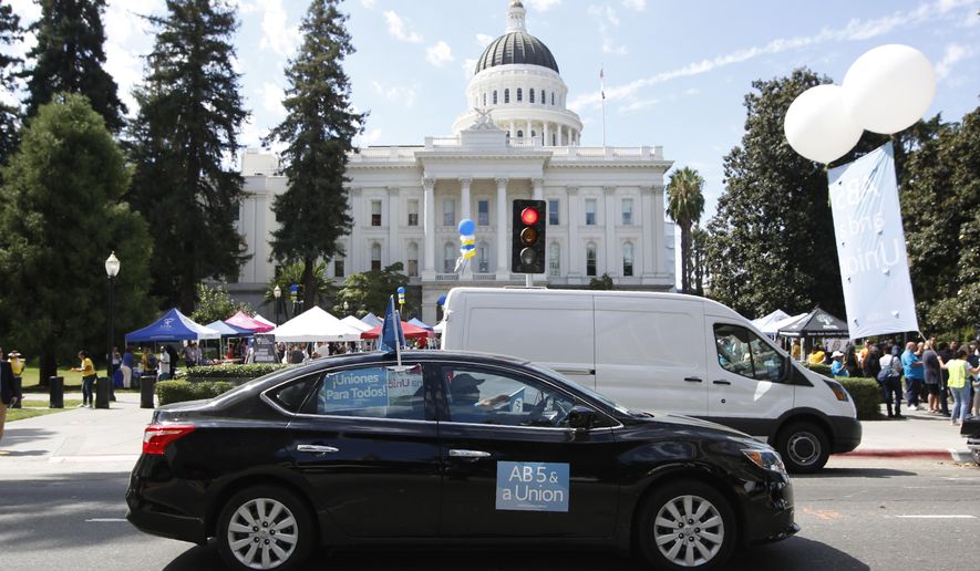 FILE — In this Aug. 28, 2019 file photo supporters of a measure to limit when companies can label workers as independent contractors circle the Capitol during a rally in Sacramento, Calif. Gov. Gavin Newsom signed a measure, to take effect in 2020, making it harder for industries to treat workers like contractors instead of employees who are entitled to minimum wage and other benefits. Uber, Lyft and DoorDash have said they'll spend $30 million to put an initiative on the 2020 ballot to overturn the law. (AP Photo/Rich Pedroncelli, File)