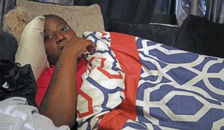 In this Dec. 18, 2019 photo,  Crystal Roberts curls up on a friends sofa after being evicted from her subsidized apartment at Fort Myers, Fla., Southward Village earlier in the day,  a week before Christmas. Roberts, who is disabled and suffers chronic bronchitis, is one of a growing number who residents allege the City of Fort Myers Housing Authority has evicted in order to avoid giving them vouchers as it is required to do when it tears down the aging complex and replaces it with new, mixed income housing. (Andrew West/The News-Press via AP)